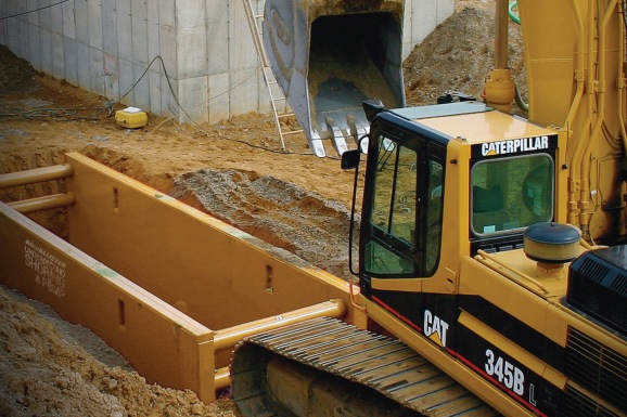 Cat excavator with shoring in the trench